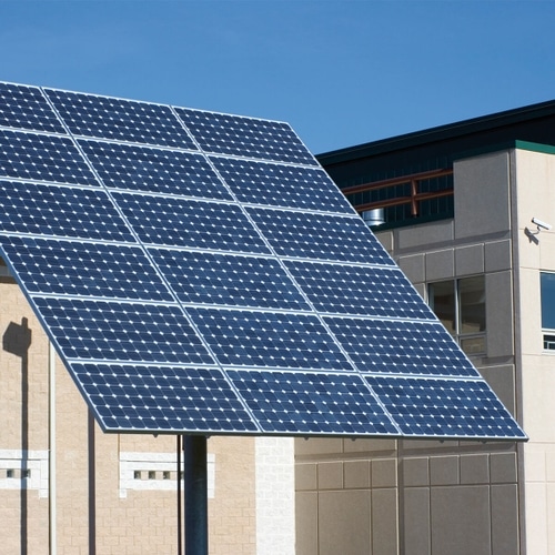 Ein Bild eines Solarpanels vor einem Gebäude. Die Installation dieses Solarpanels trägt dazu bei, Kosten zu sparen und verbessert das Energiemanagement des Gebäudes.